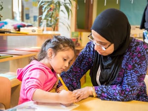 Teacher helping child with her writing skills