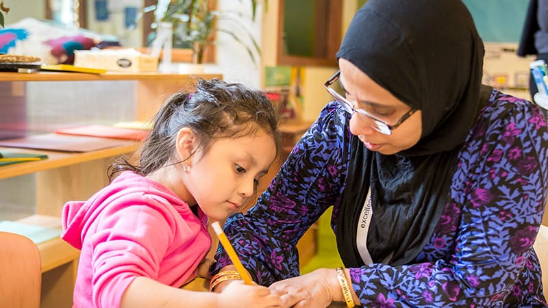 Teacher helping child with her writing skills