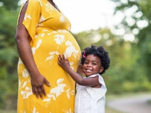 Young child holding mother's pregnant belly