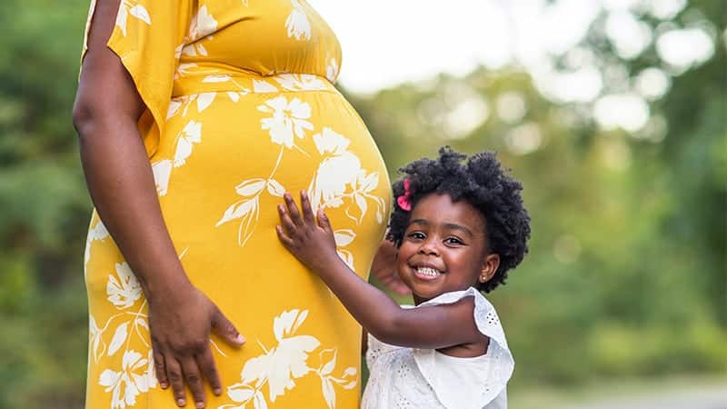 Young child holding mother's pregnant belly