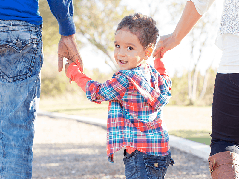 Little boy holding hands with both parents