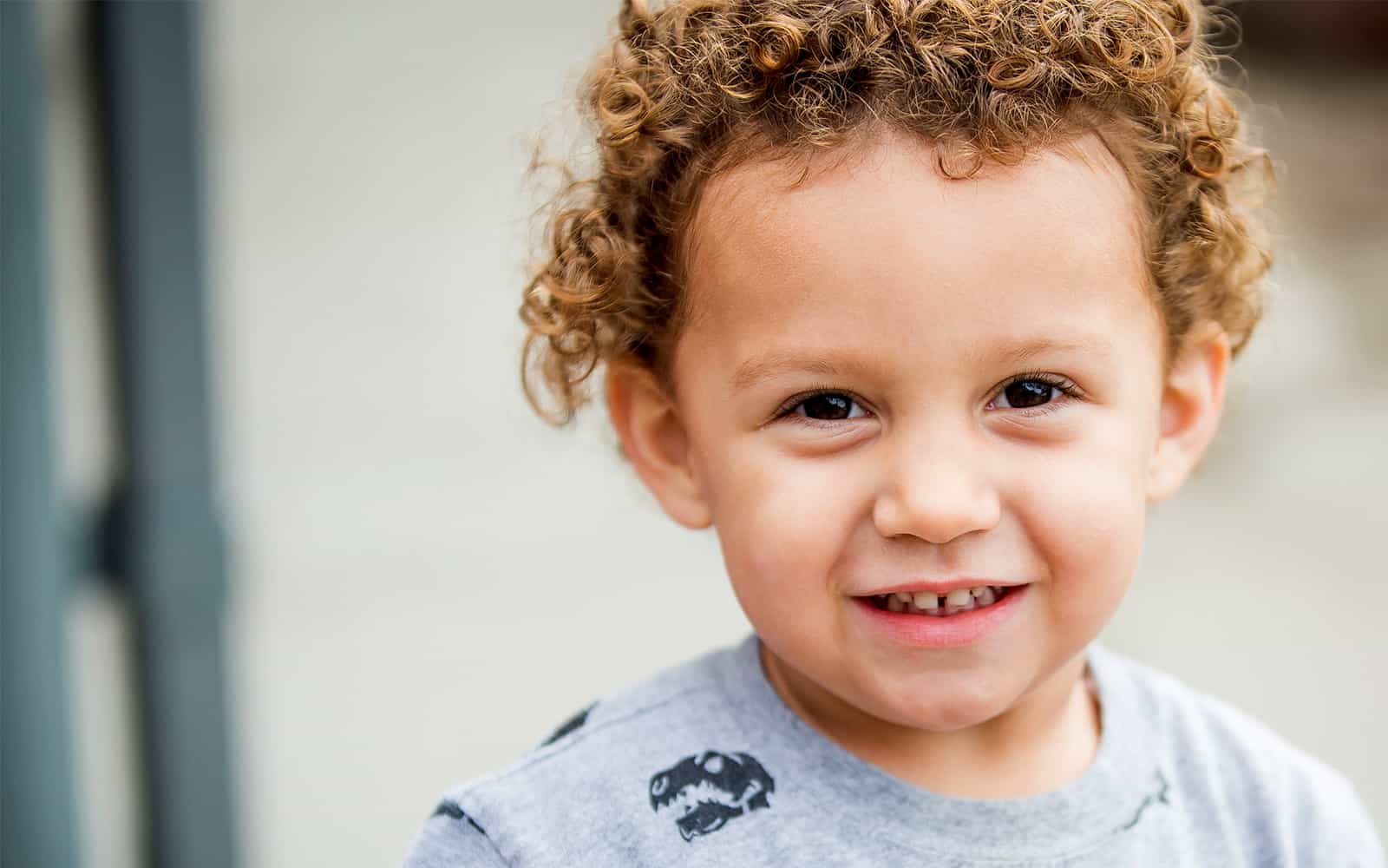 Young child in grey sweatshirt smiling