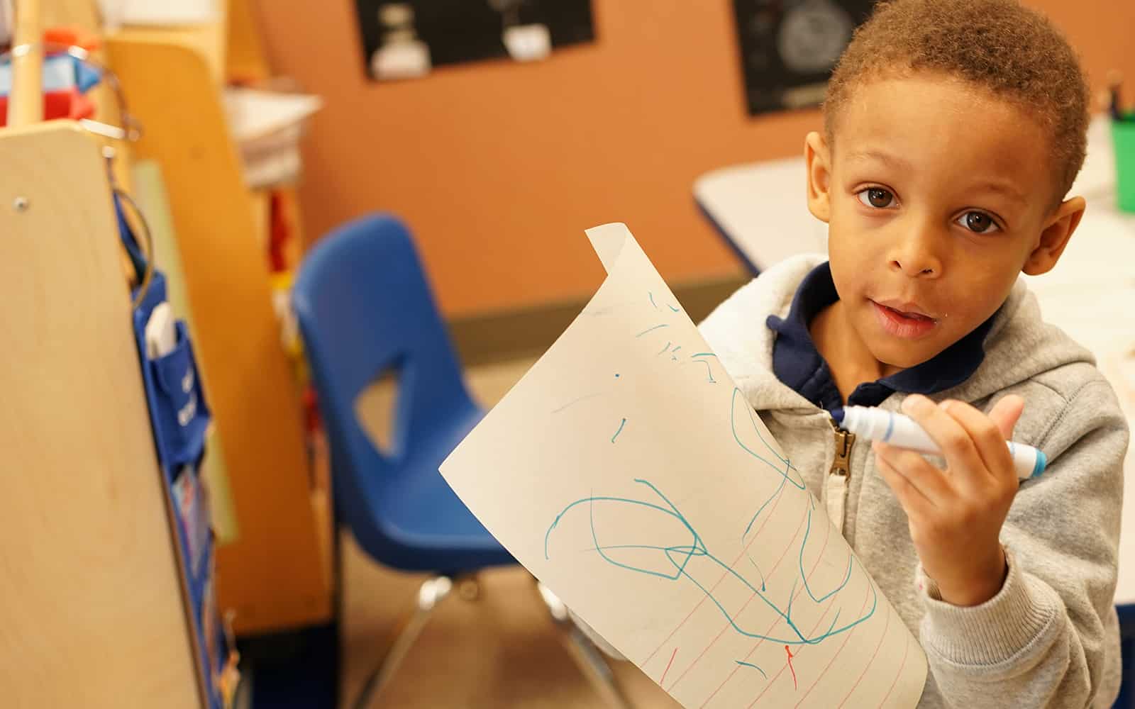 Educare boy drawing on paper with marker