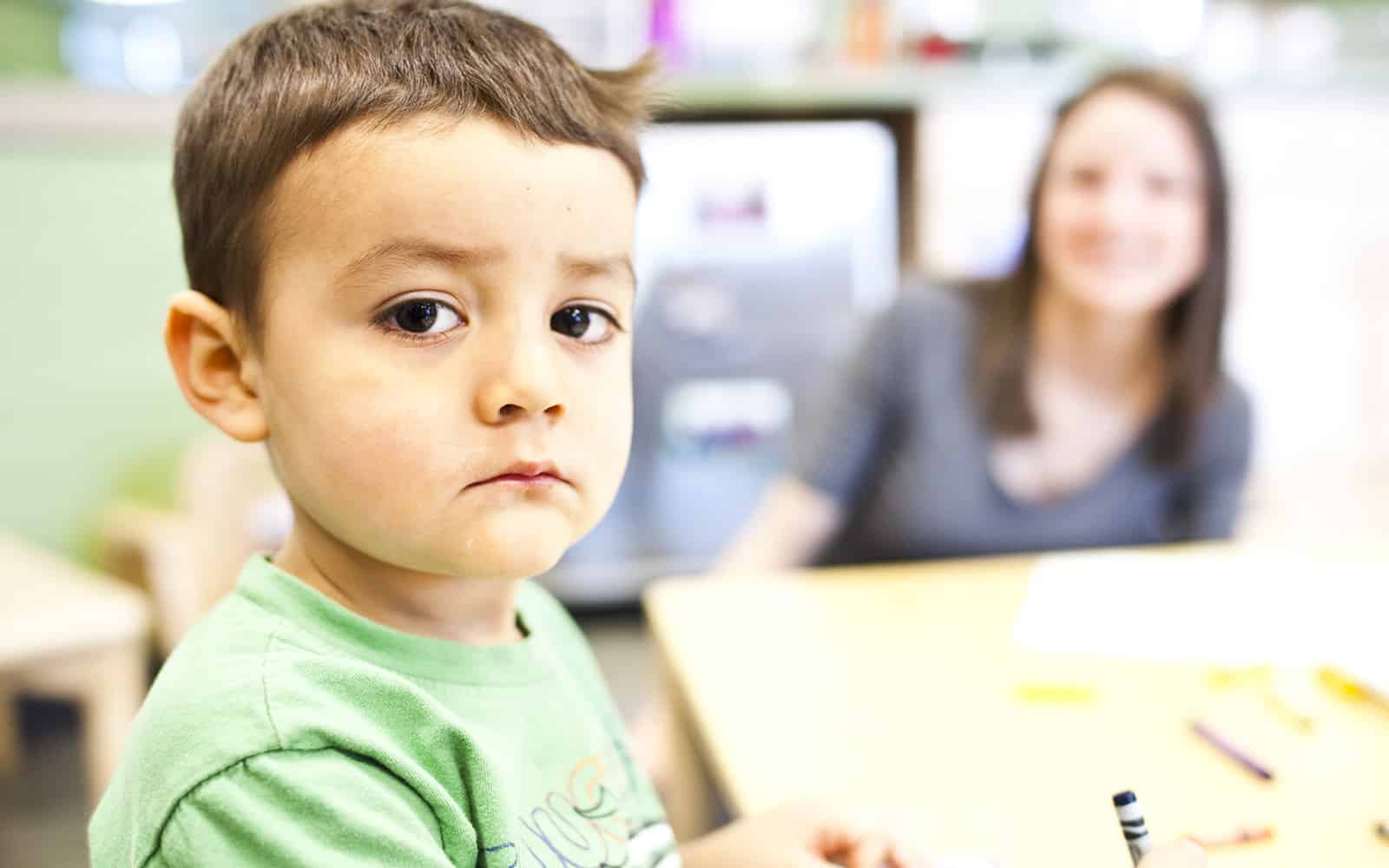 Educare boy sitting at table looking into camera