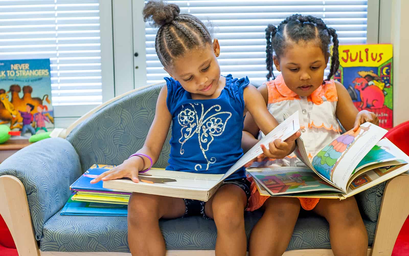 Two Educare girls reading books on sofa