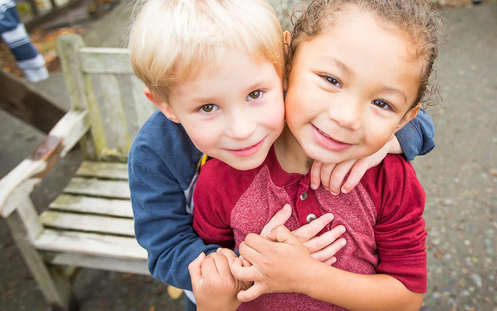 Two boys smiling and hugging outside