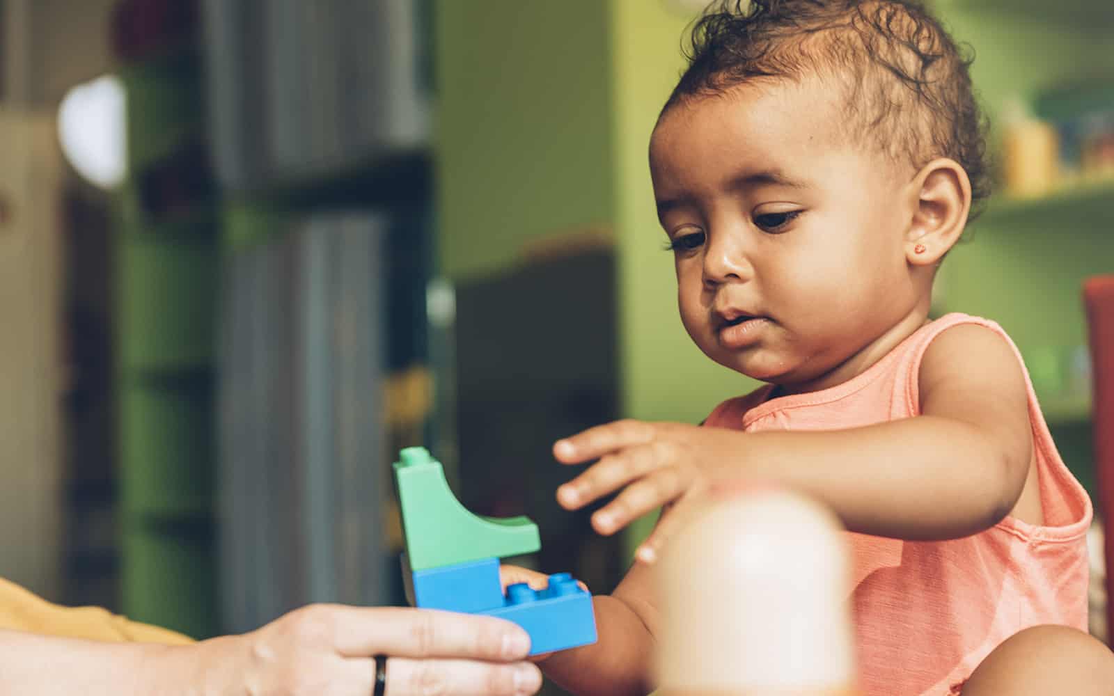 Little girl in orange dress playing with blocks