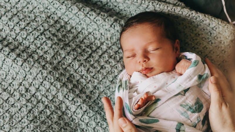 Newborn baby swaddled laying on blanket