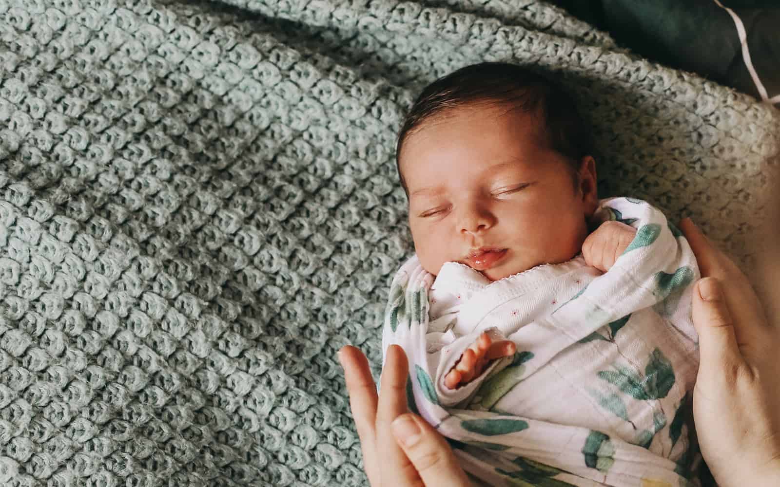 Newborn baby swaddled laying on blanket