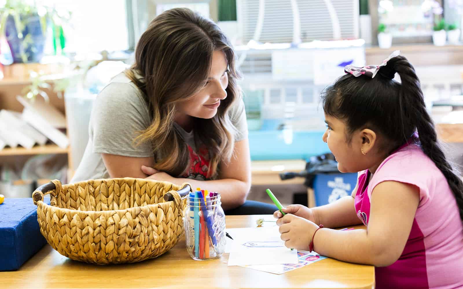 Teacher working with little girl at table