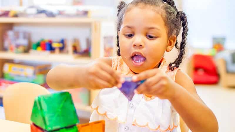 Little girl playing with shapes in classroom