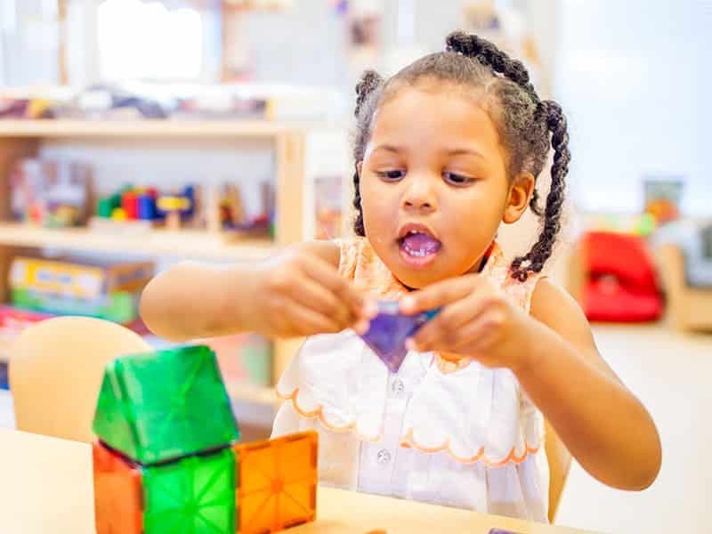 Little girl playing with shapes in classroom