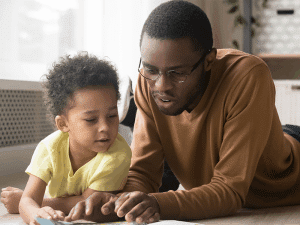 Young boy reading with adult 