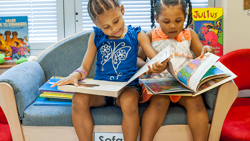 Two girls reading on couch