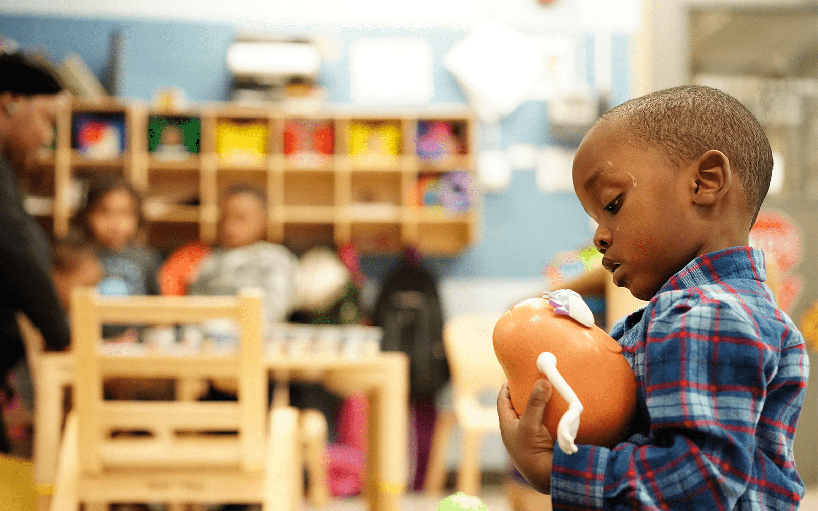 Little boy playing with mr. potato head toy in classroom