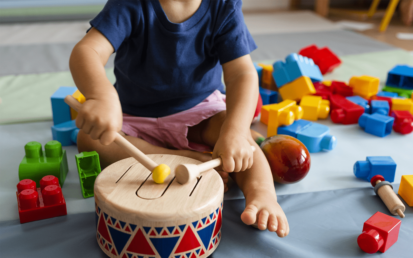 Child playing with a drum set toy