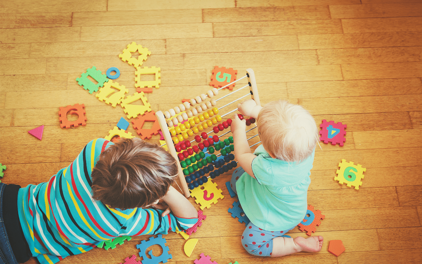 Young child and baby play with early learning toys