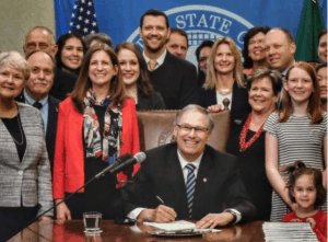 Close up of Gov Inslee with the caption “Pre-COVID bill signing. So many smiles!”