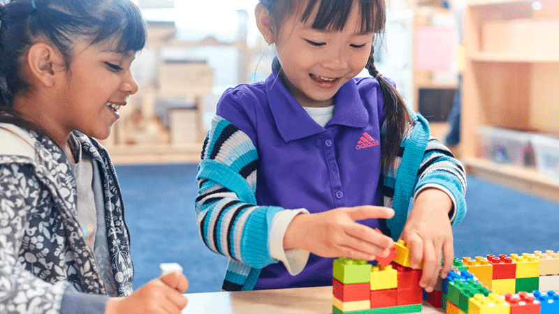 Two children playing legos in classroom