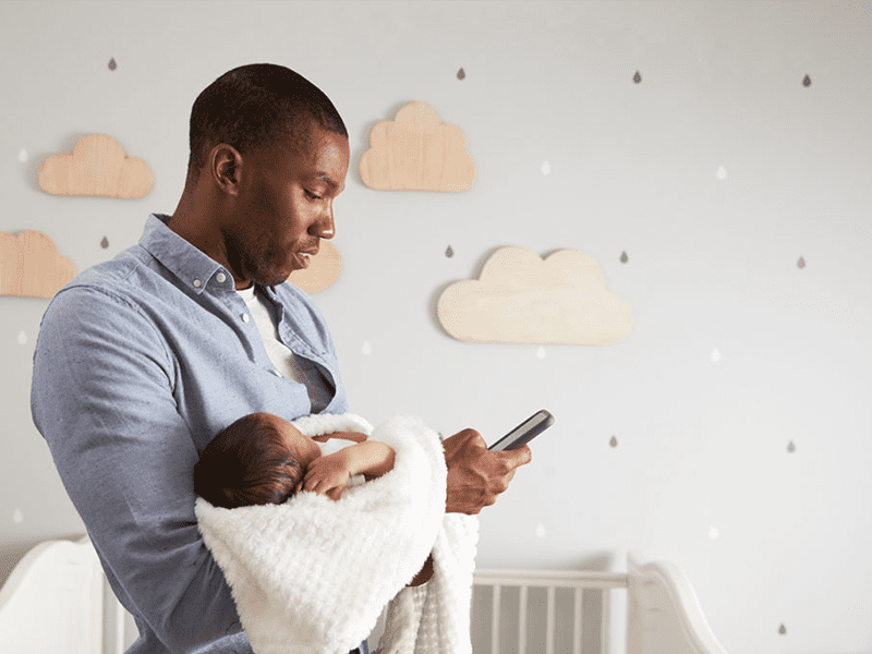 Father holding child and looking up article on phone