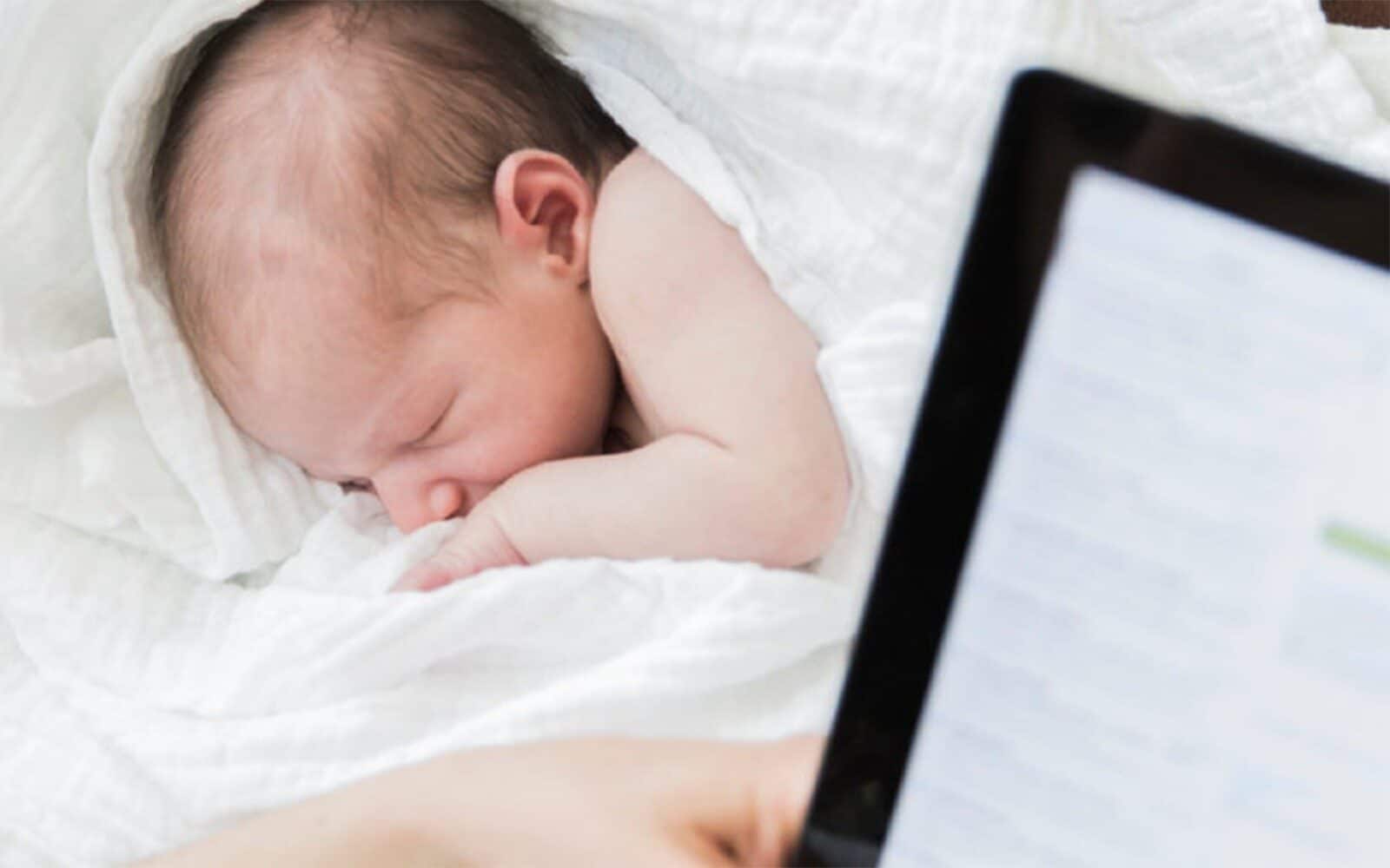 Parent reading tablet while baby sleeps