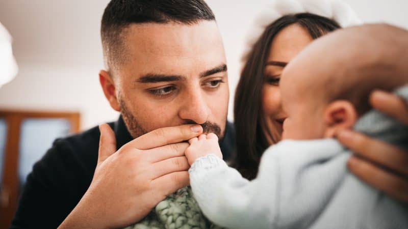 Parents kissing baby's hand