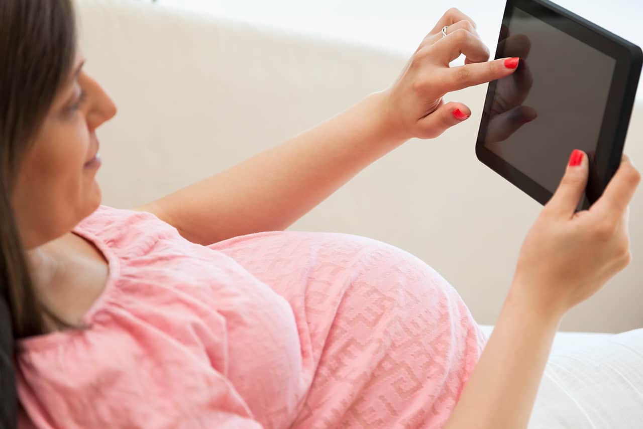 Pregnant woman researching on tablet