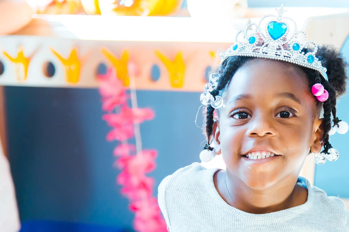 Child smiling at camera wearing tiara