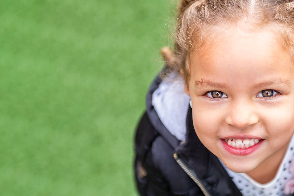 Child smiling at camera with green background