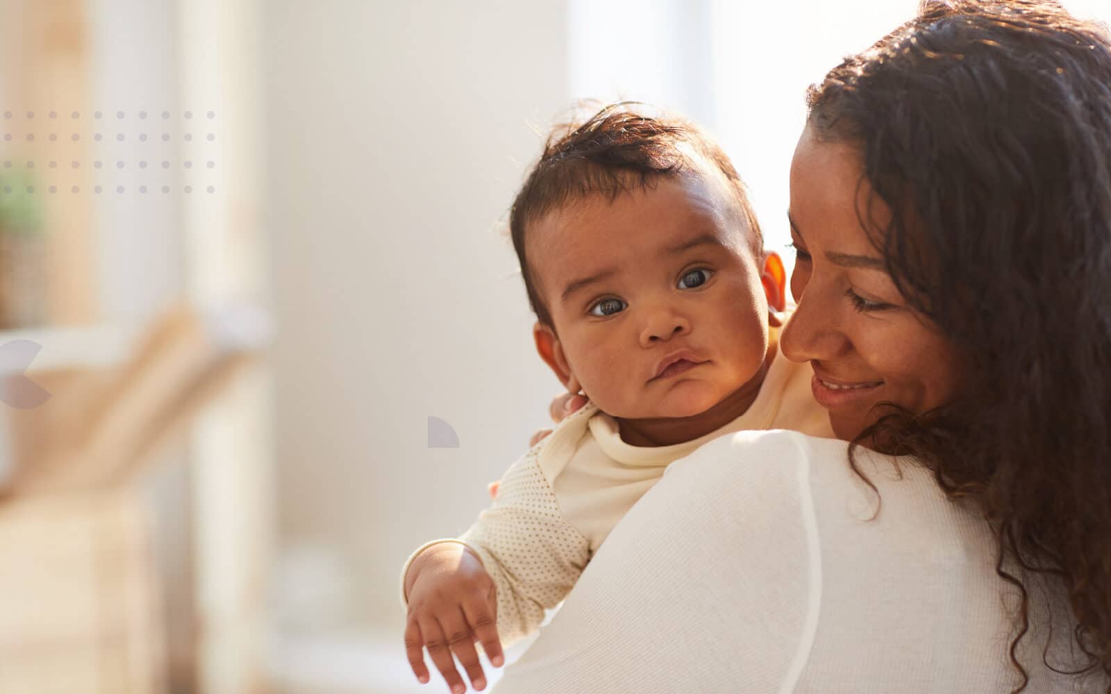 Mother holding infant and smiling at them