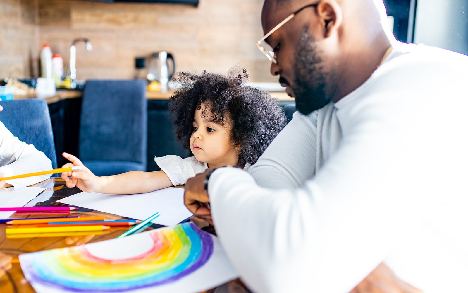 Image of a father painting rainbows with his daughter