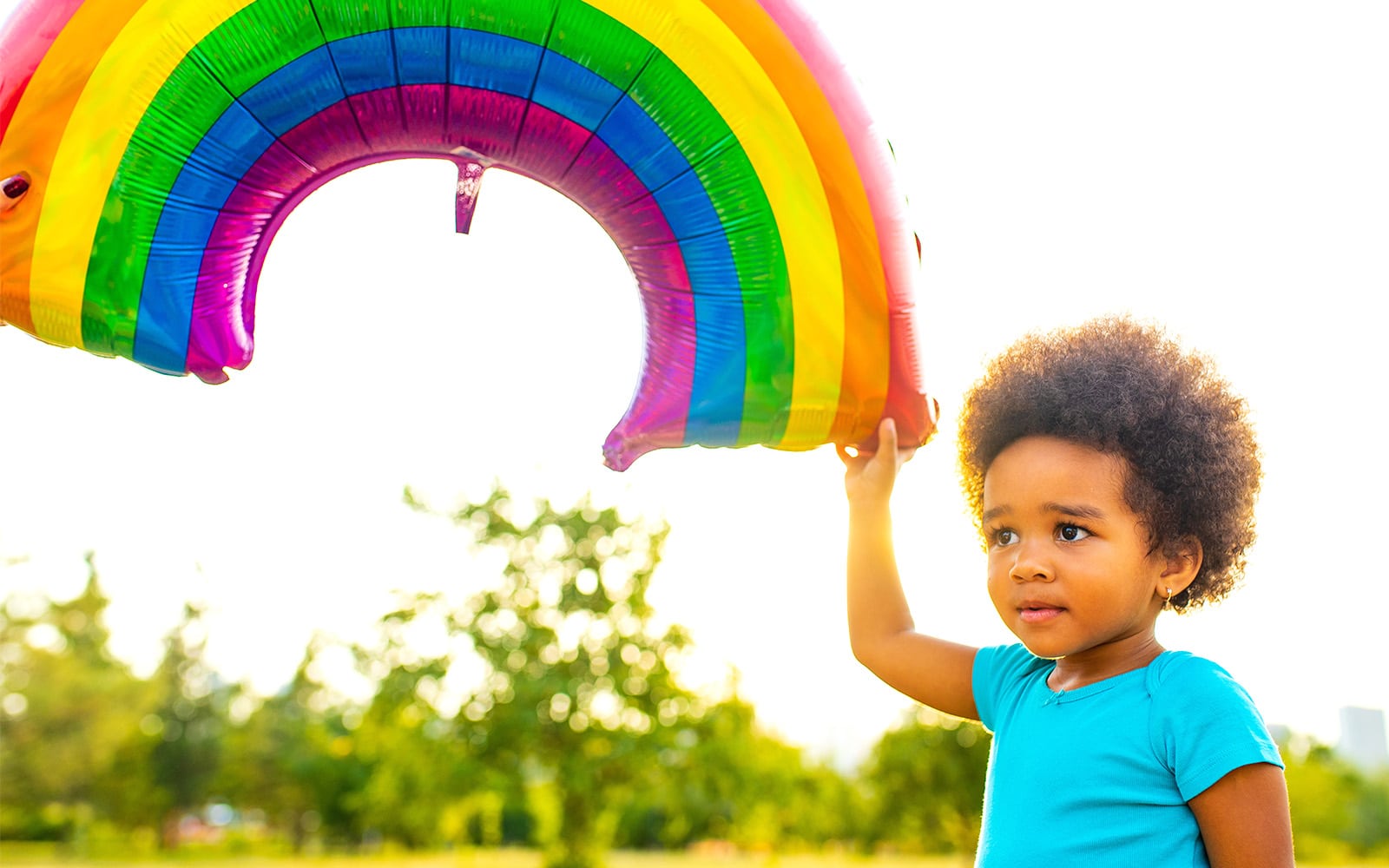 Image of a little girl holding a rainbow balloon