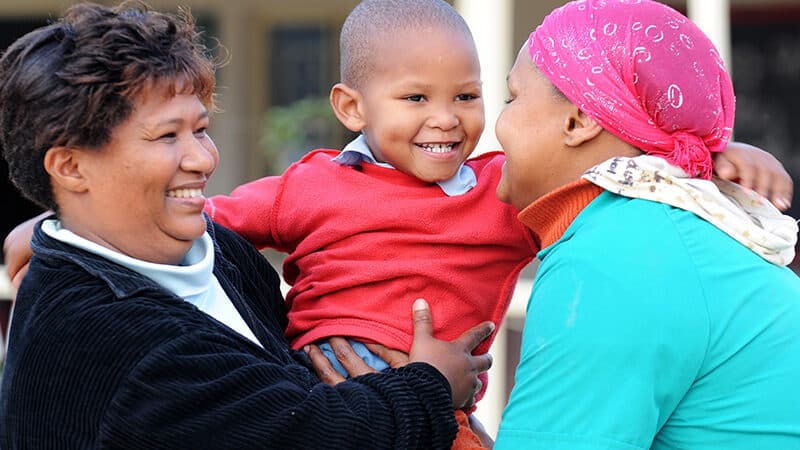 A parent and family professional holding a child while smiling