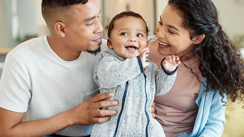 A Mother and father looking at their child with joy