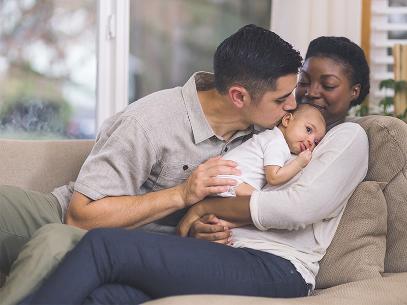 Father kissing child while mother is holding them