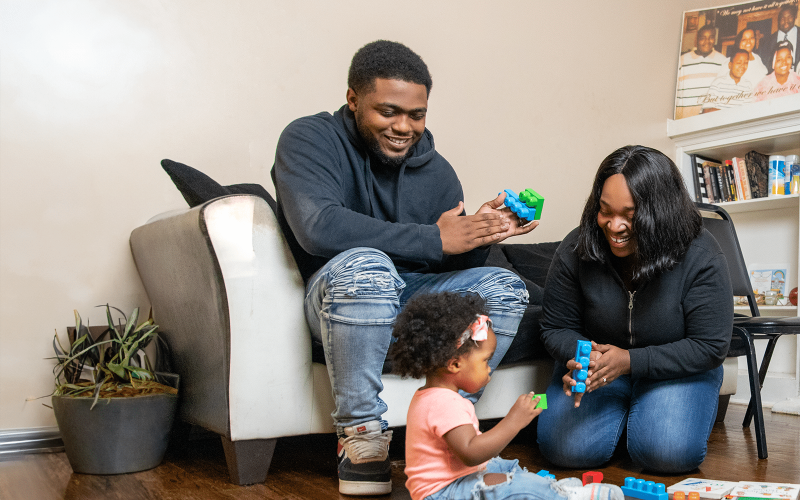 parents sitting on floor playing with child