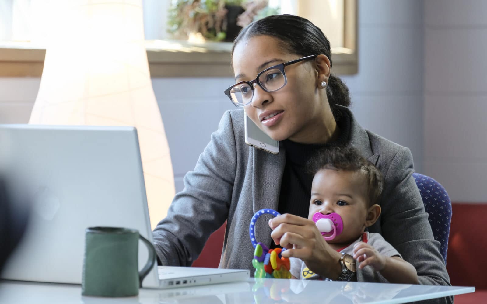 Mother holding baby and working at her computer