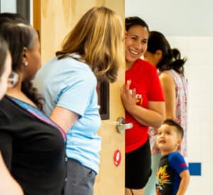 Teachers standing at door greeting parent leaving with child