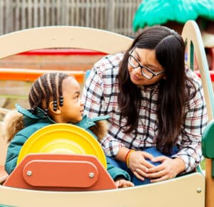 Child playing outdoors with caregiving