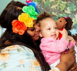 Caregiver holding child who is holding a doll