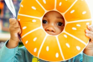 Little boy looking through donut toy designed like orange slices.