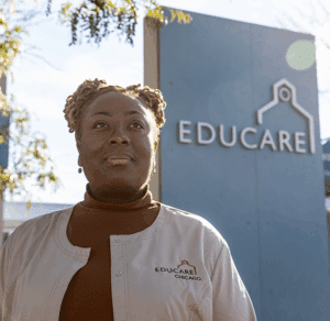 A photo of Danielle Jordan earlier in her career. She is wearing a tan Educare Chicago branded smock and a turtleneck.