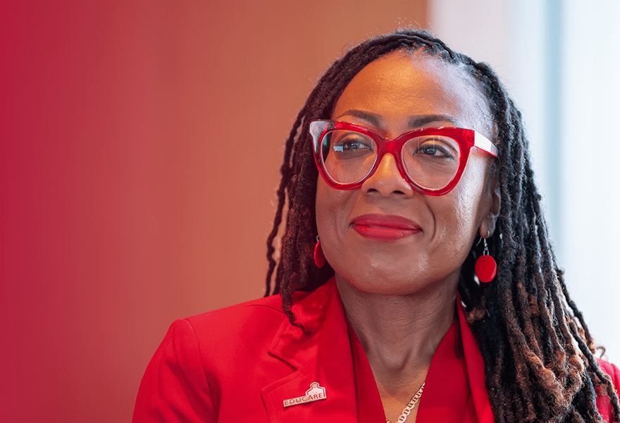 Danielle Jordan at 25th anniversary symposium, wearing a red blazer and red glasses.