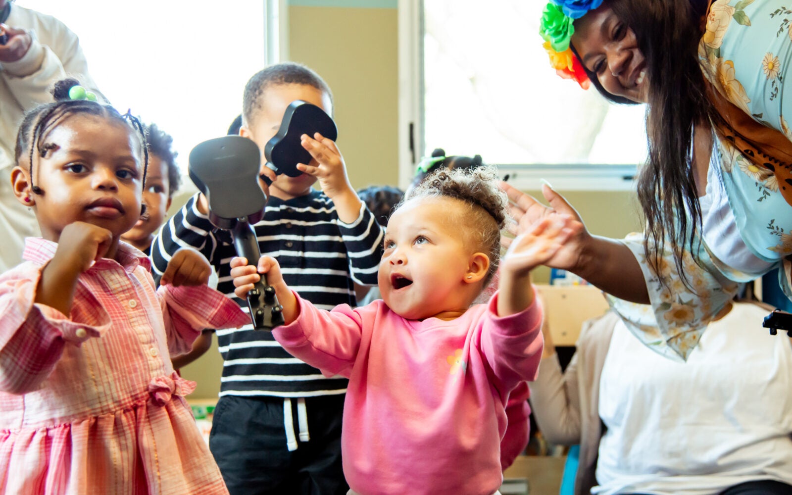 Providers and children dancing with instruments in an Educare Chicago classroom.