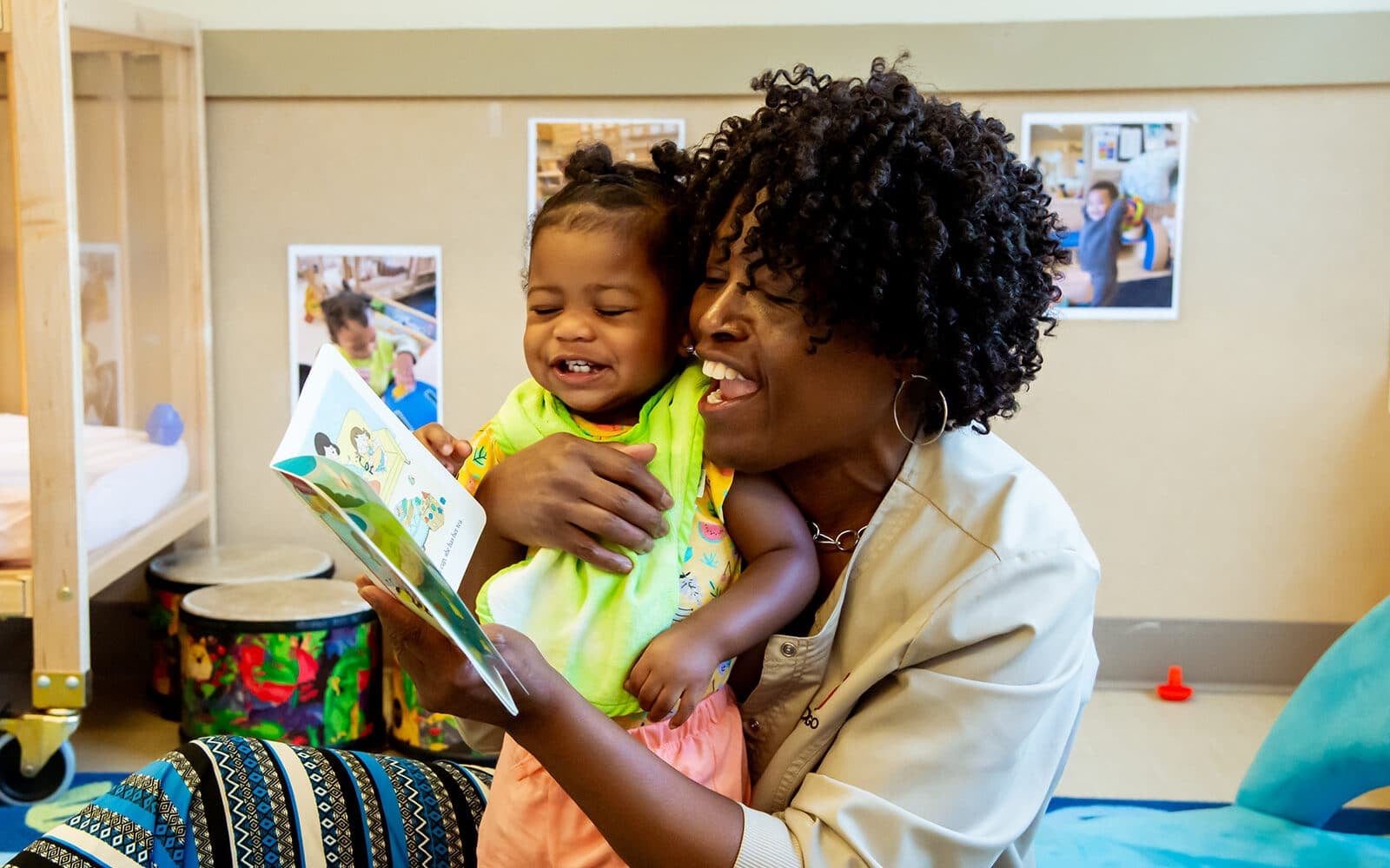 Educare teacher and toddler sitting in an embrace and reading a book.
