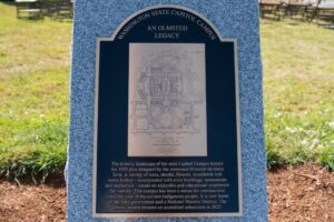 The newly installed Olmsted Legacy Marker, which is a black and bronze plaque on a whiteish gray granite pedestal.