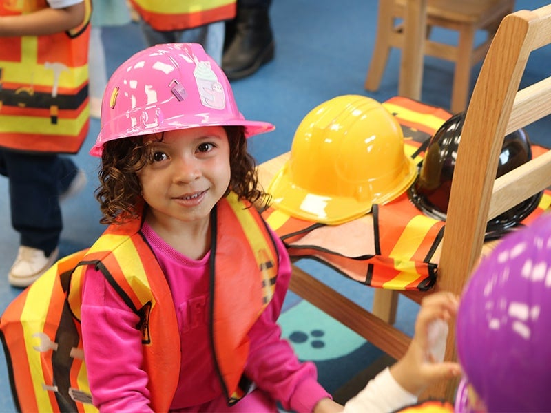 Little girl in pink construction hat looking at the camera