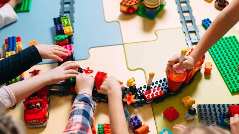 Children's hands playing with toys on the floor.