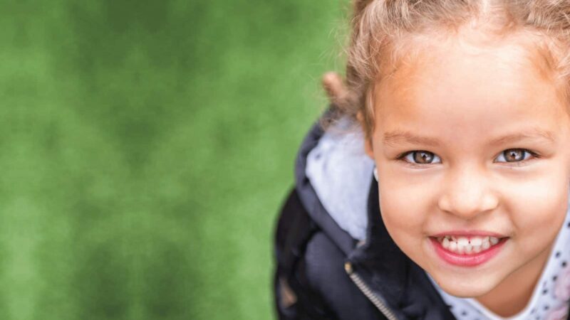 little girl smiling with grass in background